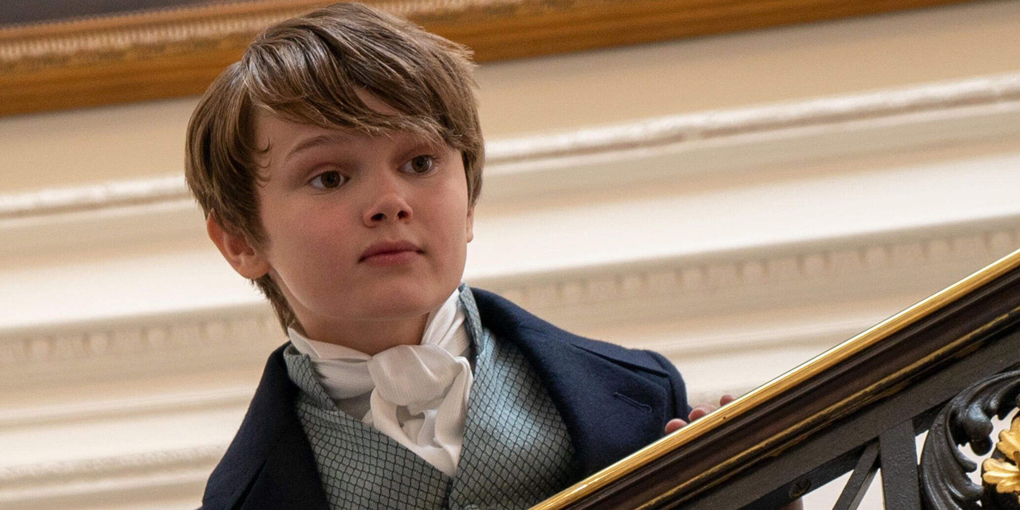 Gregory Bridgerton Stands On a Staircase and Looks Over the Handrail