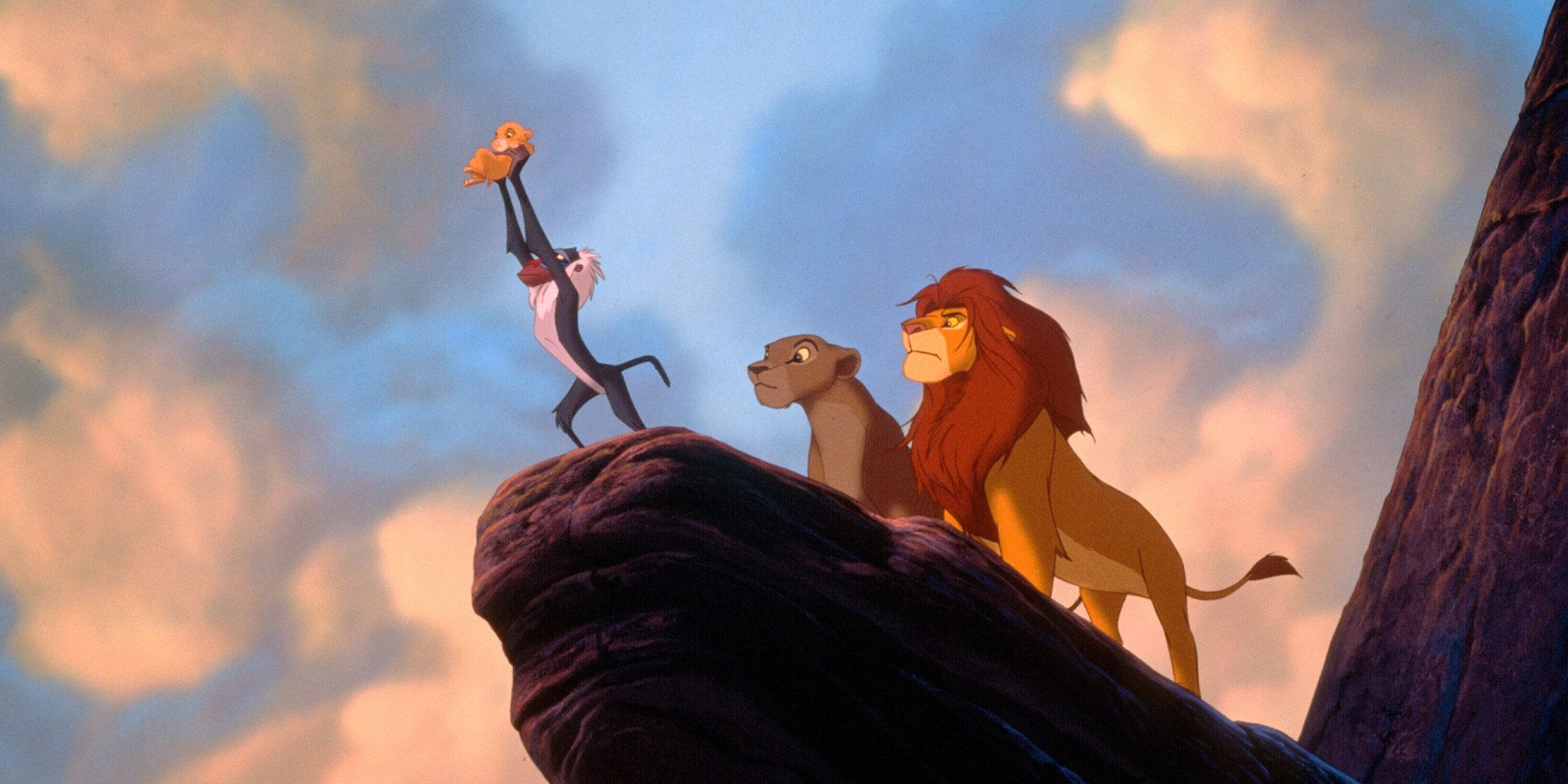 Rafiki presents Simba to the animals while atop Pride Rock with Mufasa and Sarabi looking on in The Lion King