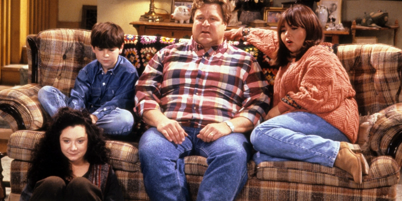 The Conner family from Roseanne watching TV on the couch.