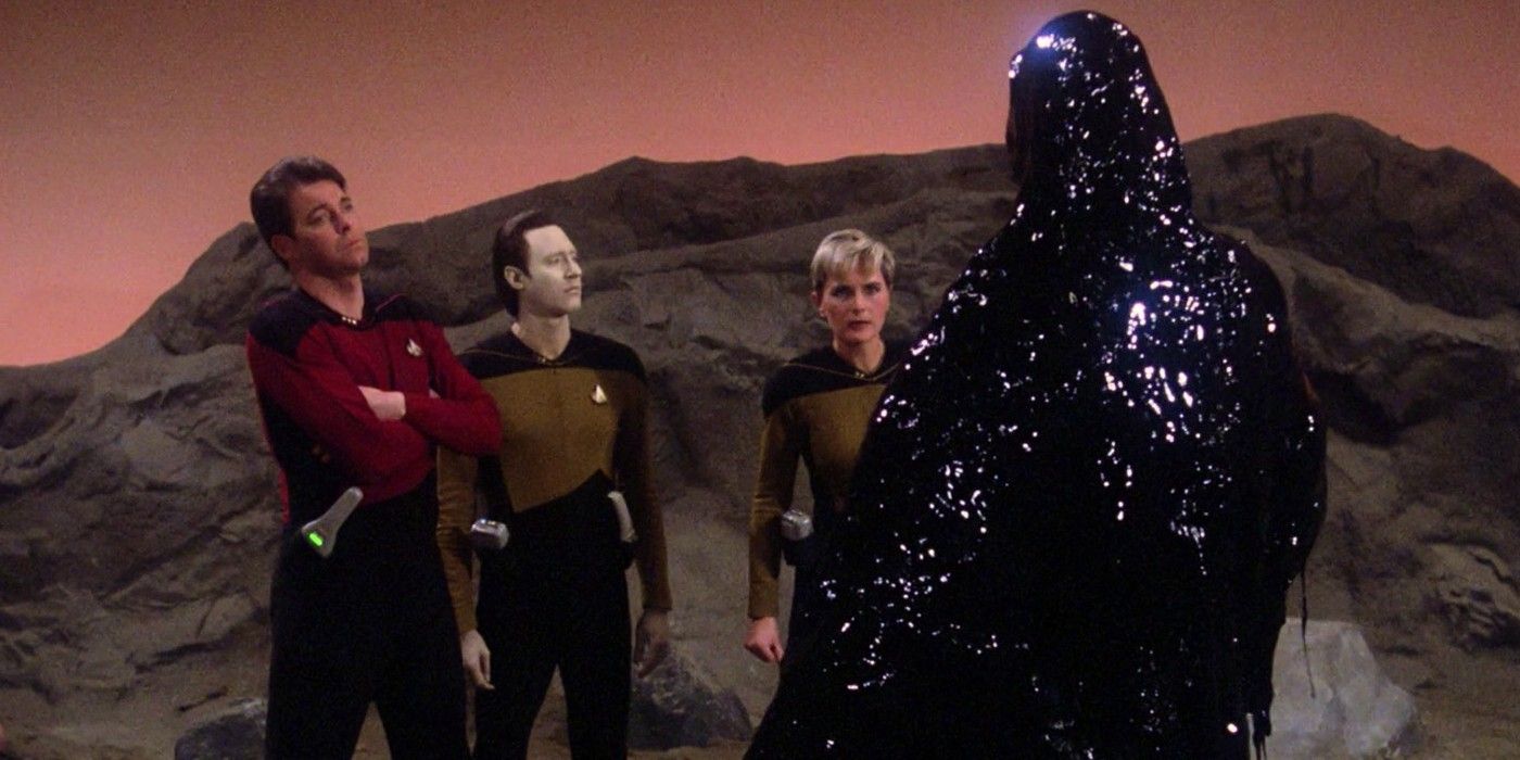 Riker, Data and Tasha Yar confront a shadowy figure on a rocky planet 