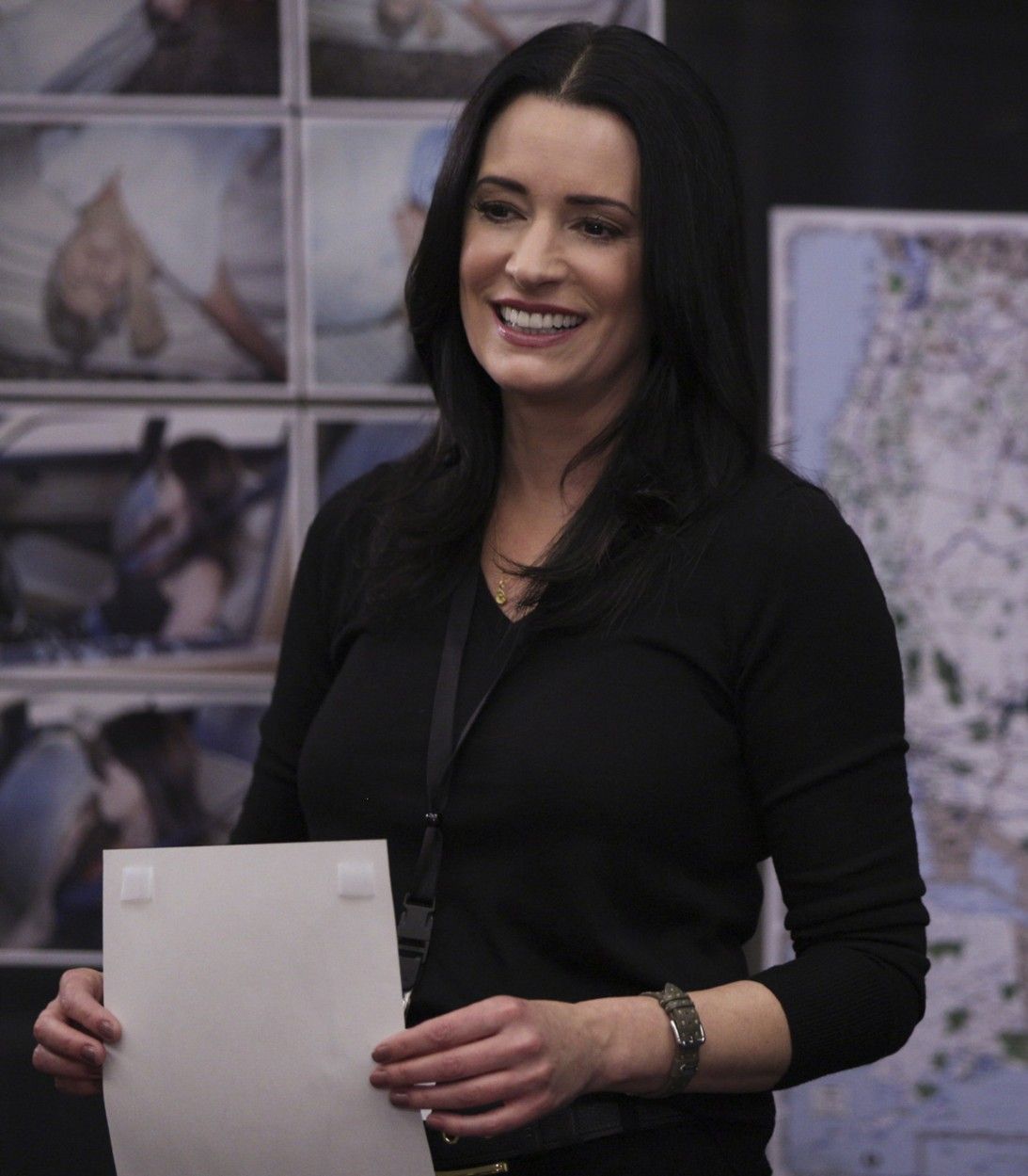 Emily Prentiss standing in front of a map and smiling on Criminal Minds