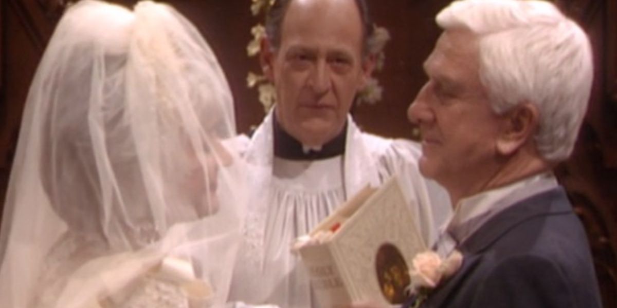 Dorothy e Lucas se encaram amorosamente enquanto um padre atrás supervisiona seu casamento 