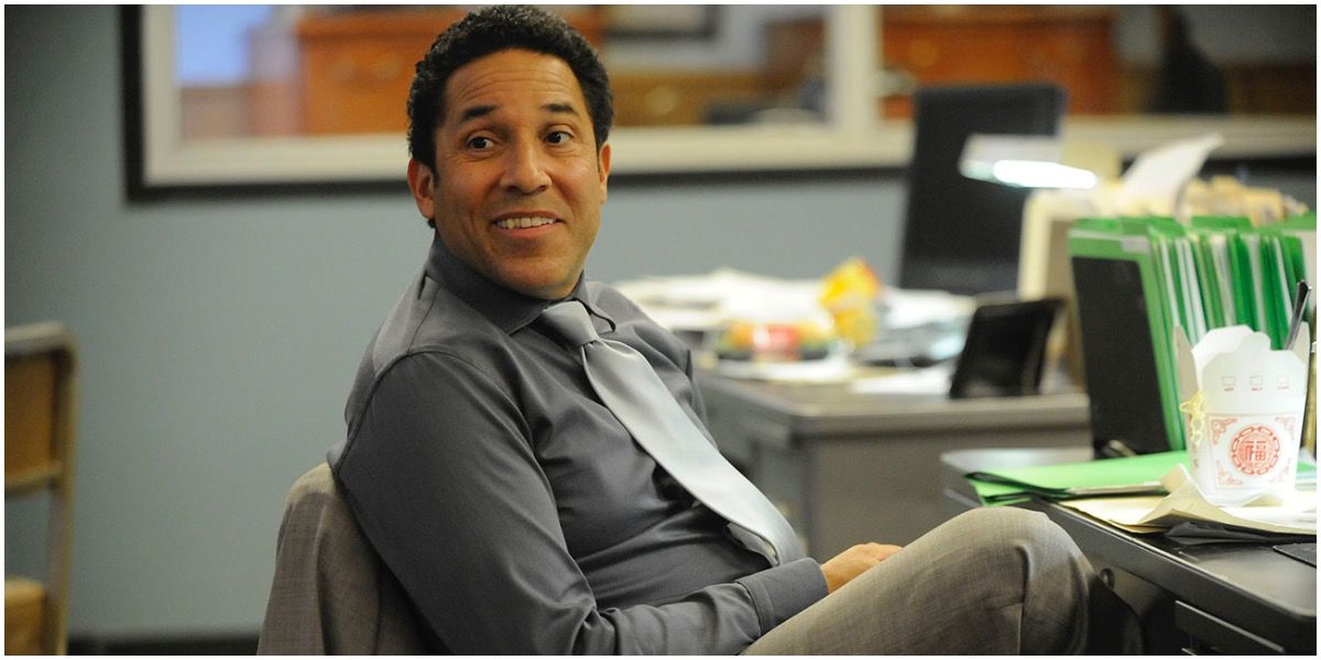 Oscar Martinez smiling on his desk in The Office