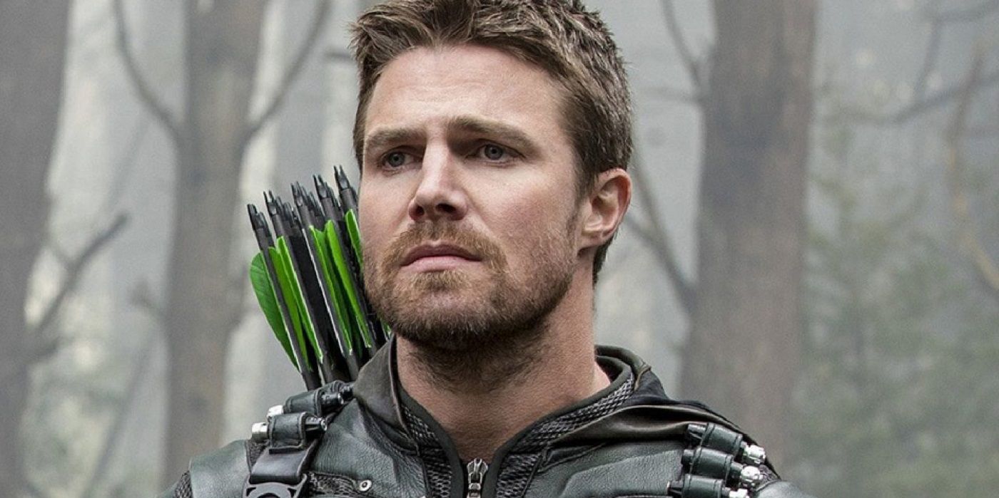 Stephen Amell stands in the woods, looks worried in Arrow