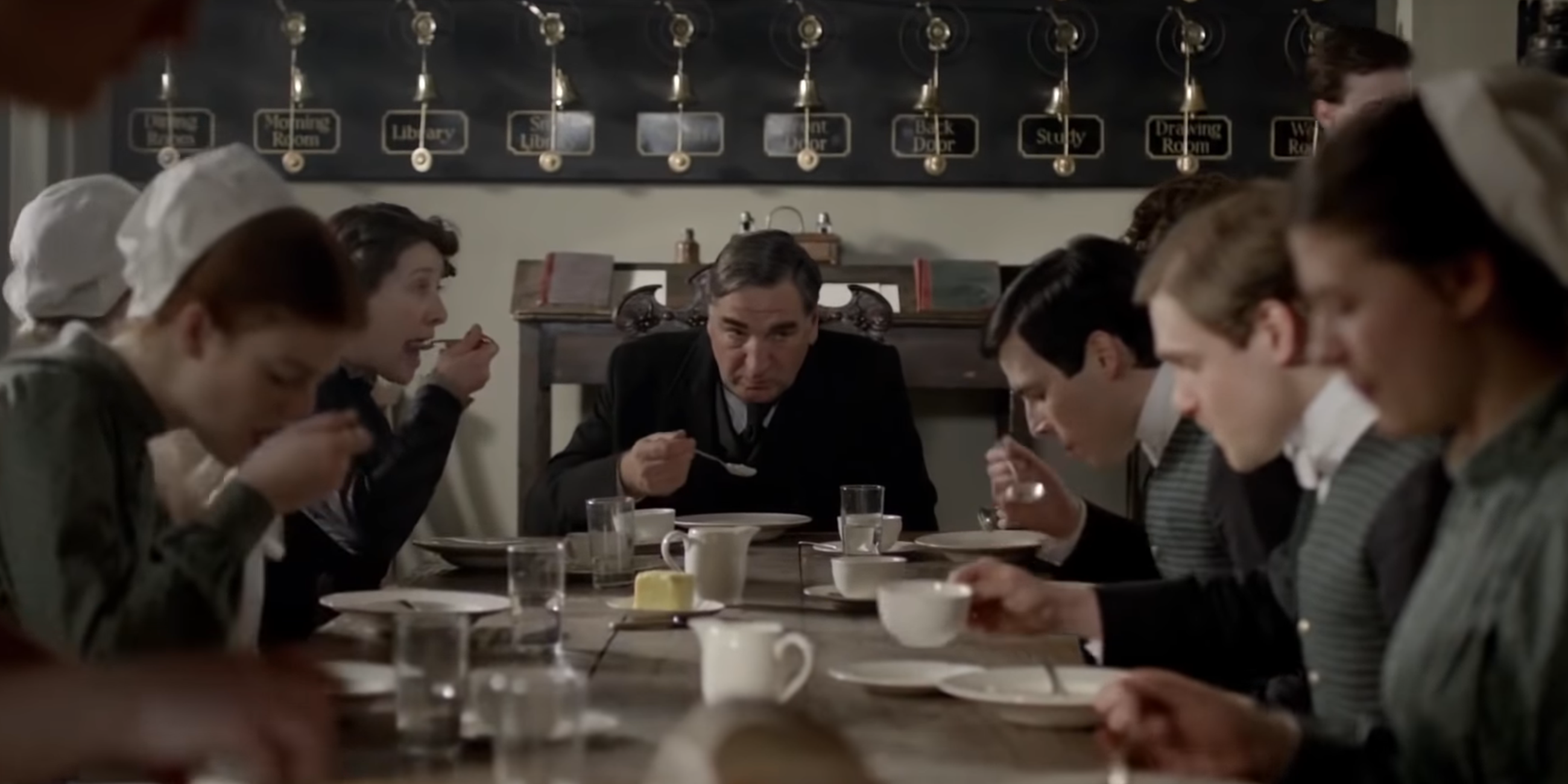 Downton Abbey's service staff eating dinner together with Carson heading the table.