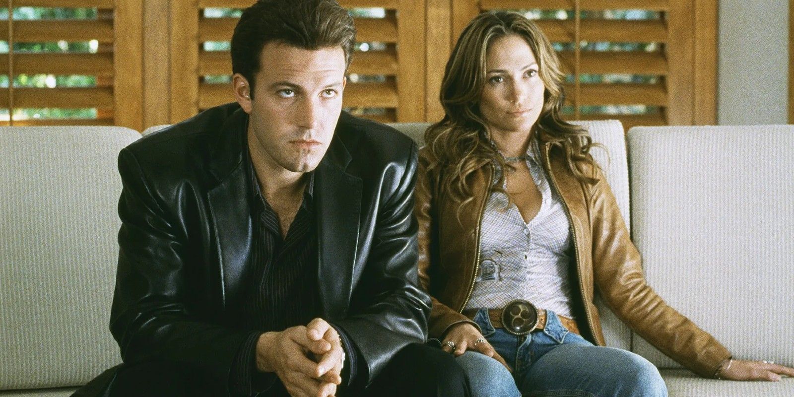 Ben Affleck and Jennifer Lopez sit side by side in Gigli