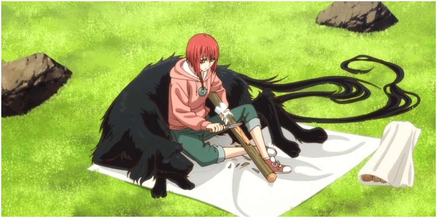 Ruth sits with Chise in a field as she carves wood