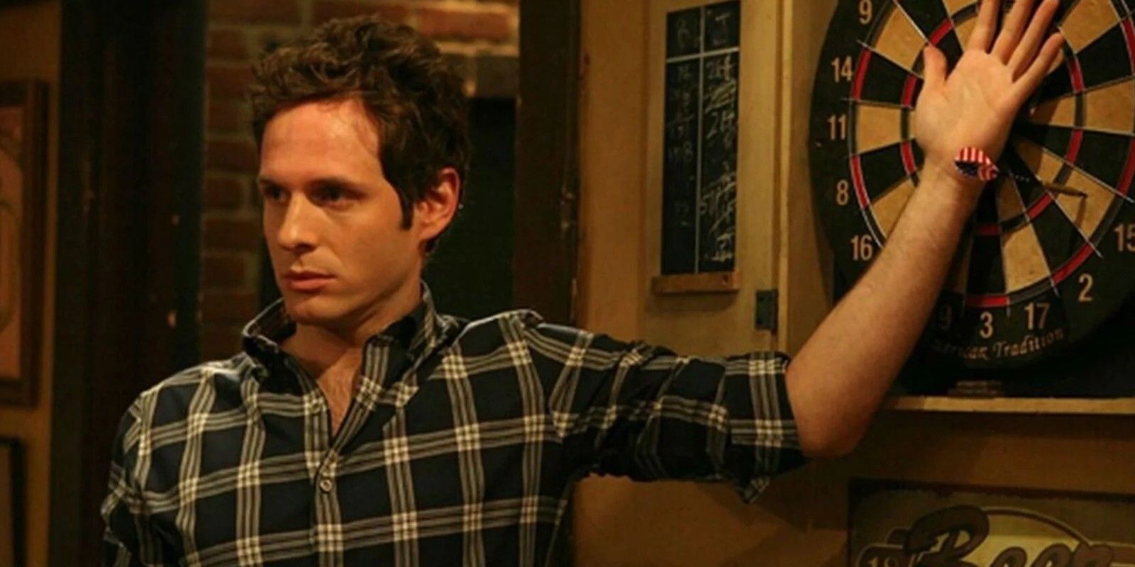Dennis Reynolds from It's Always Sunny in Philadelphia with his hand on a dartboard