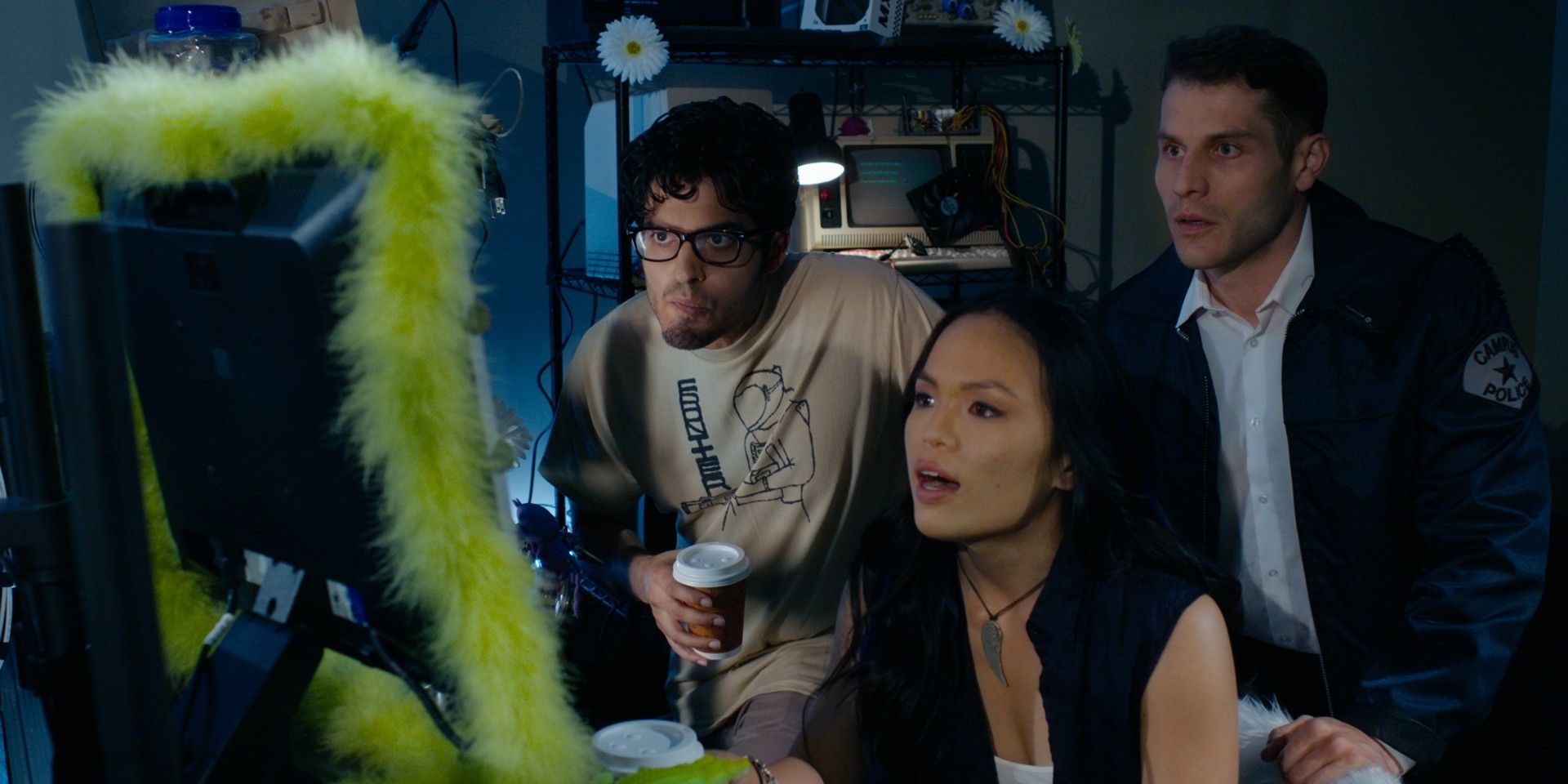 Still from Final Frequency with a computer tech sitting in front of a monitor lined in green fur and two guys standing behind her looking over her shoulder