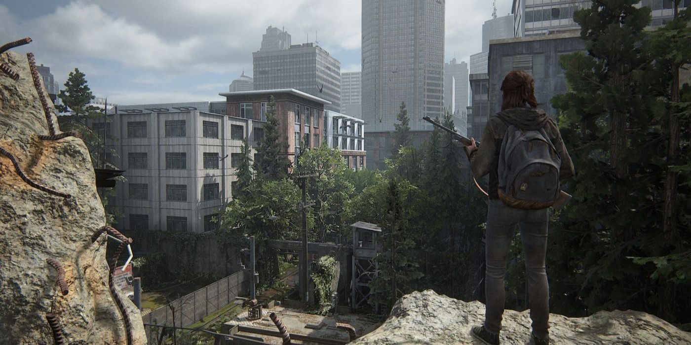 Ellie standing on a cliff, overlooking a rundown city in The Last of Us Part II