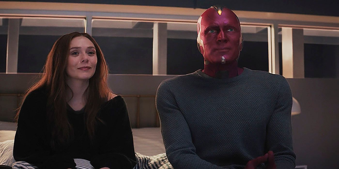 Wanda Maximoff and Vision sit on the end of a bed watching a TV (off screen).