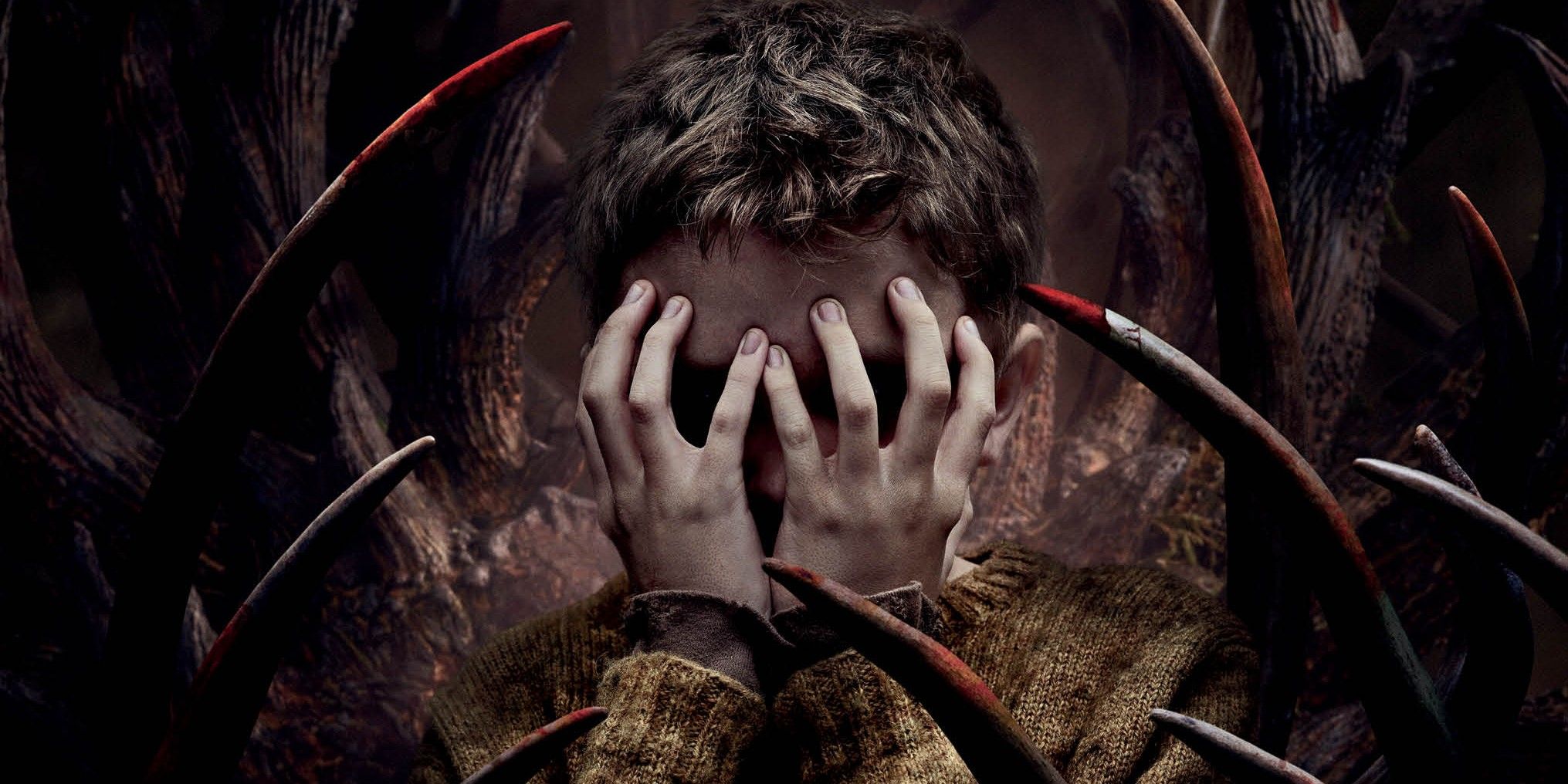 A boy hides his face in his hands in a sea of red-stained antlers