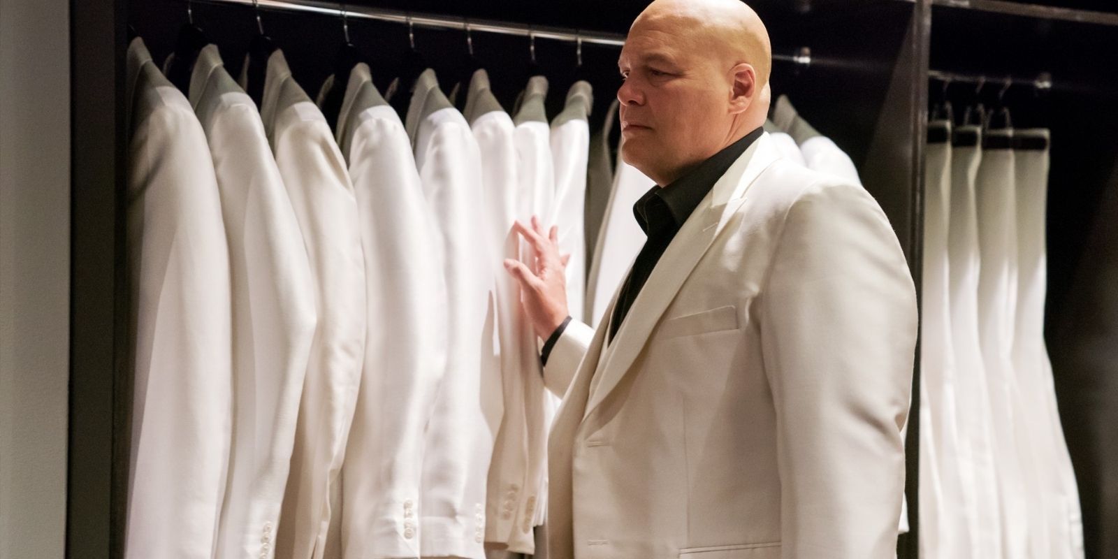 Vincent D'Onofrio as Kingpin stands in front of a wardrobe filled with white suits