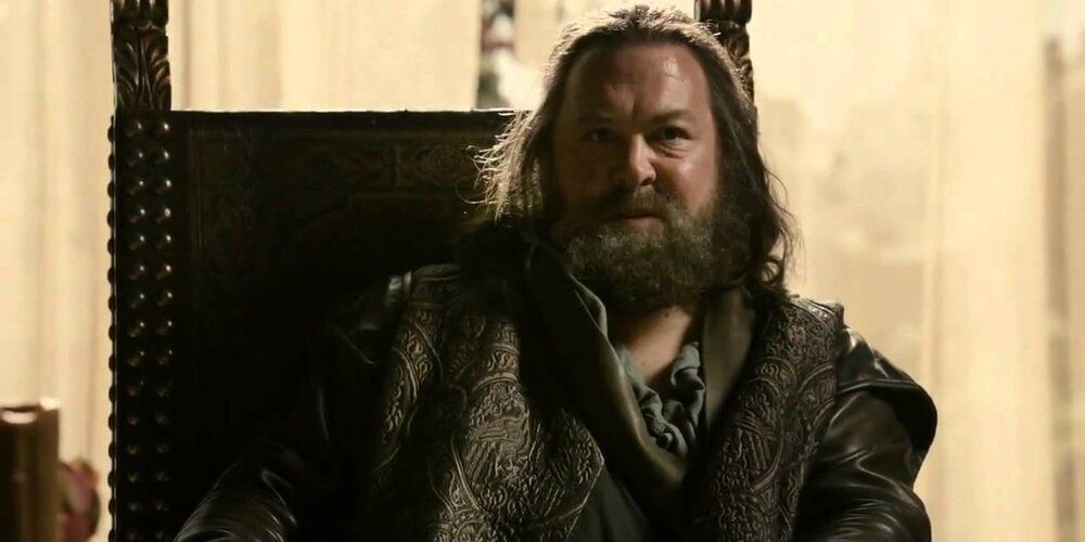 Robert Baratheon sits in a wooden chair in HBO's Game of Thrones