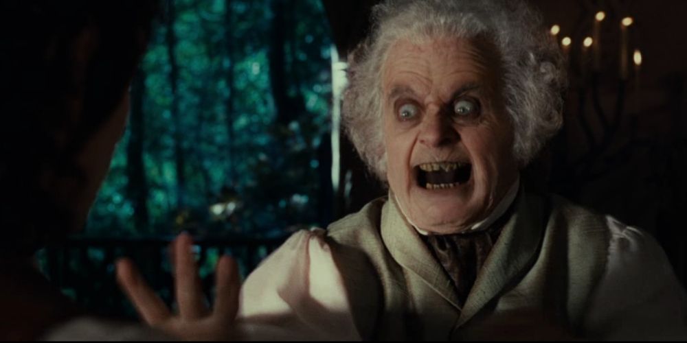 Bilbo reaches to take the ring from Frodo 