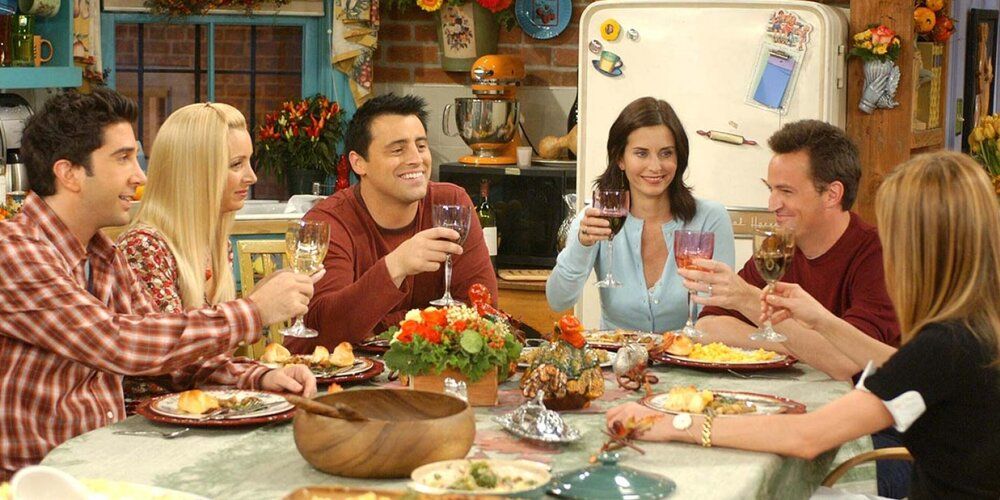 The entire cast of Friends sitting around the dinnner table enjoying themselves