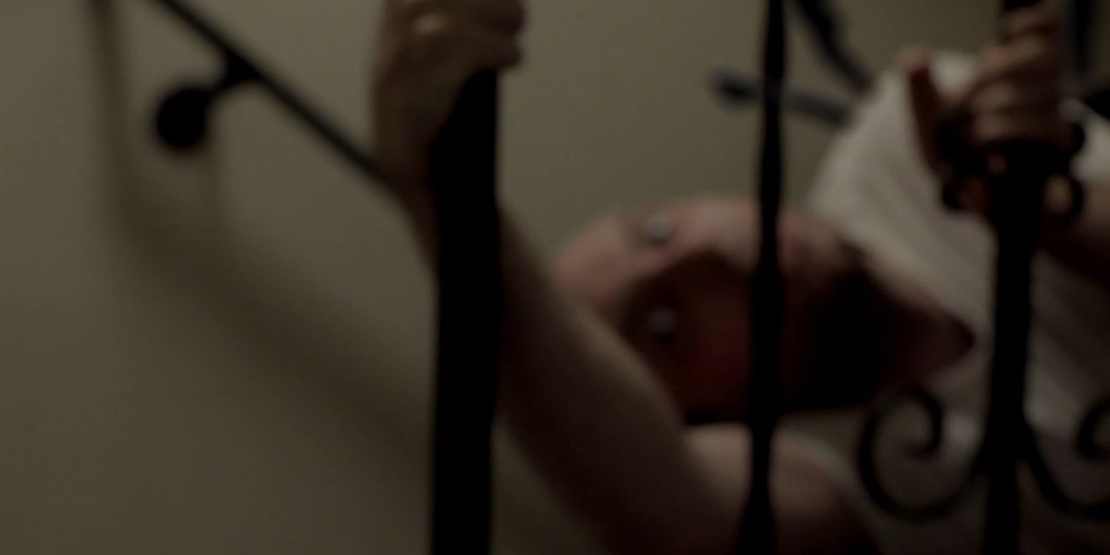 The troll takes Daniel back in Absentia. The image is purposefully blurry. Daniel grips the stair railing as the offscreen troll, seen only as two spider like fingers, tries to pull him away.