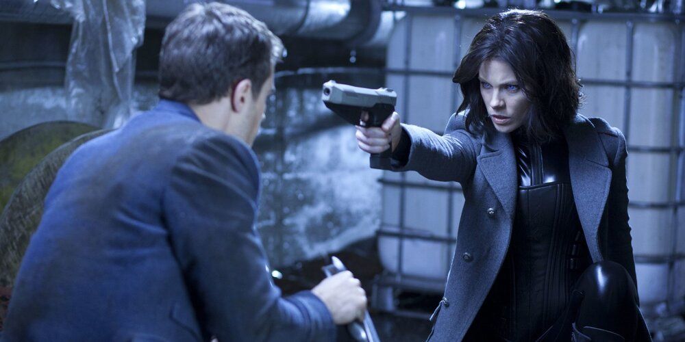 A vampire pointing a gun at another person in Underworld: Awakening
