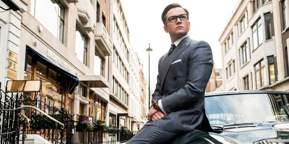 Eggsy in his sit leaning on a car in Kingsman: The Secret Service