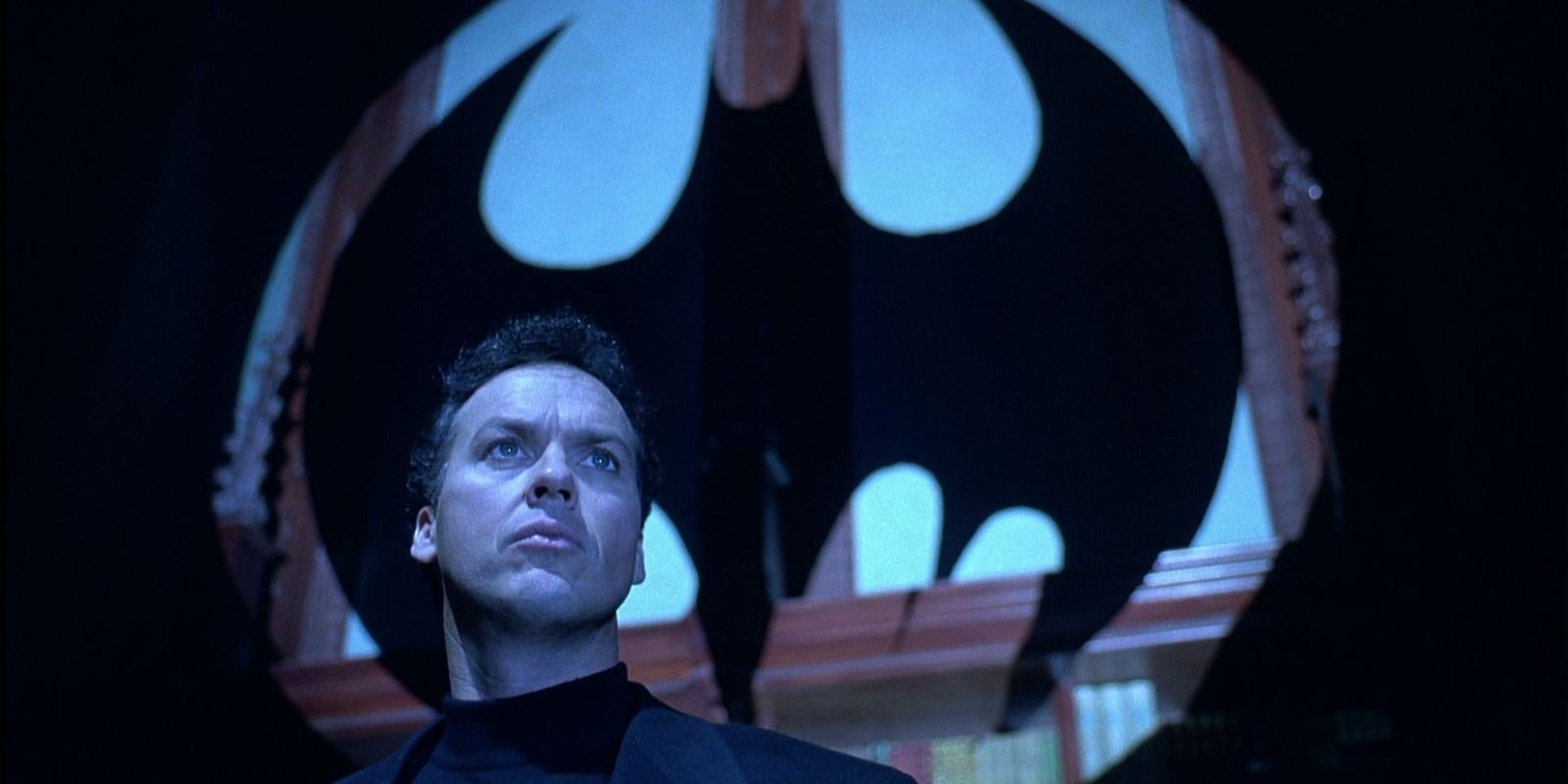 Michael Keaton's Bruce Wayne in front of the Batman symbol