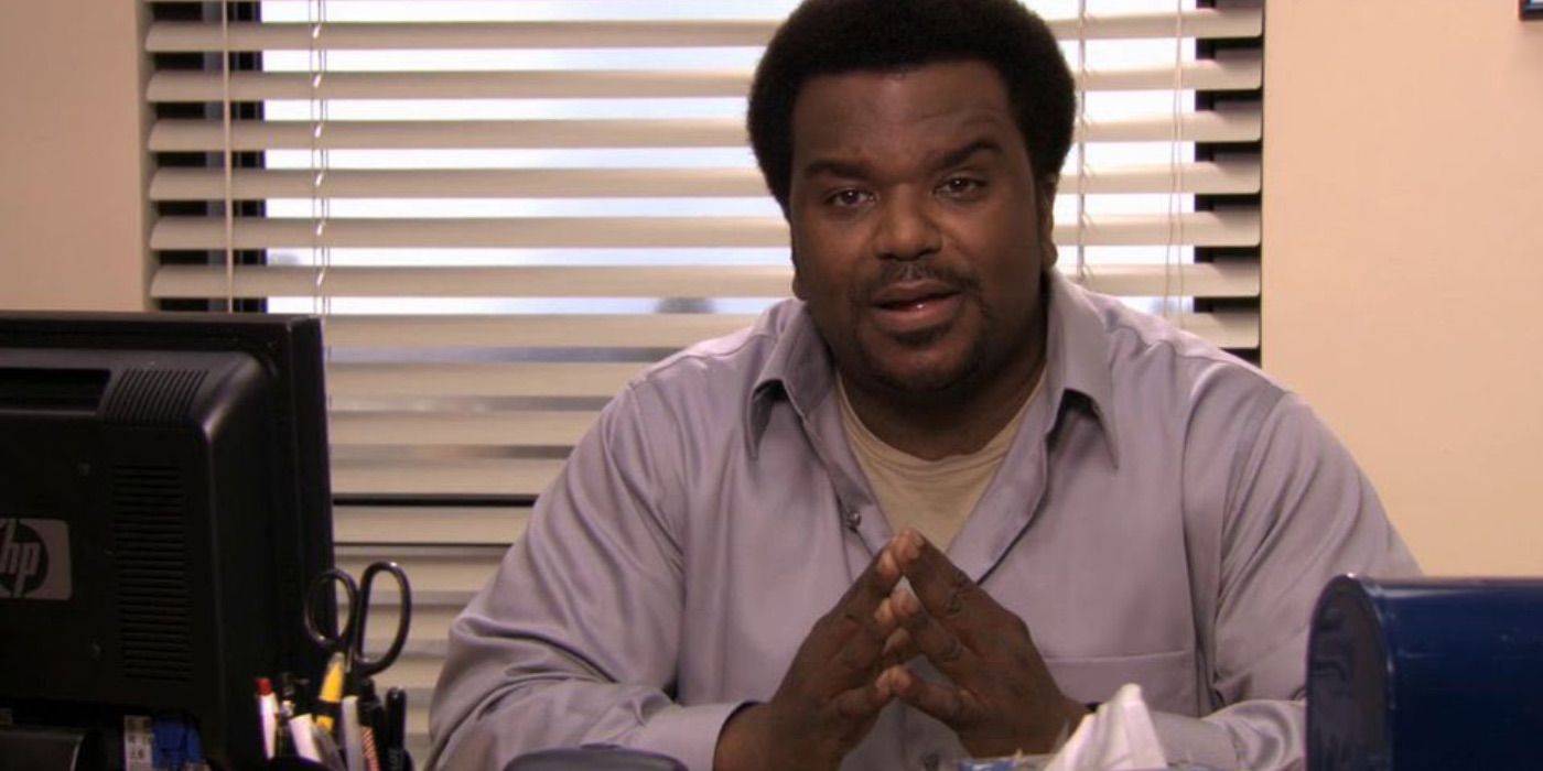 Darryl Philbin smiling sitting at his desk in The Office