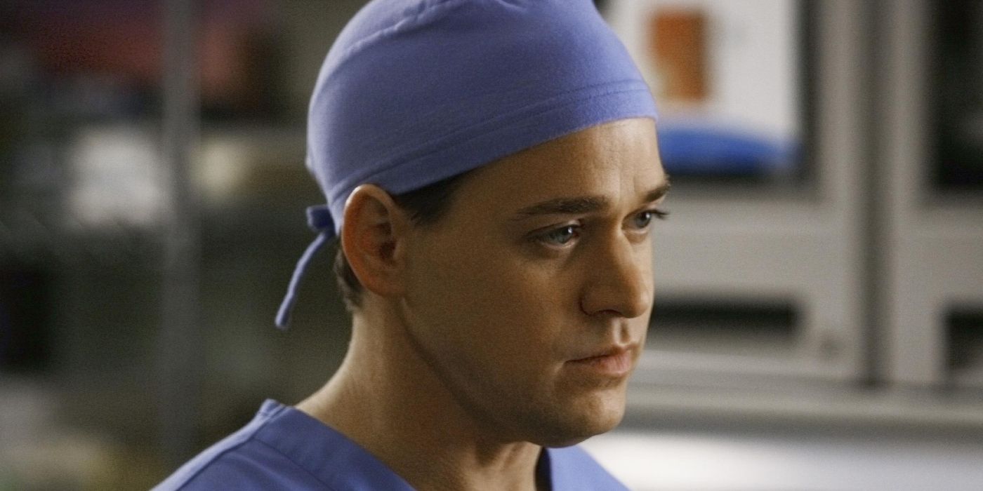 George O'Malley looking to the side with a neutral expression and scrub cap on in Grey's Anatomy.
