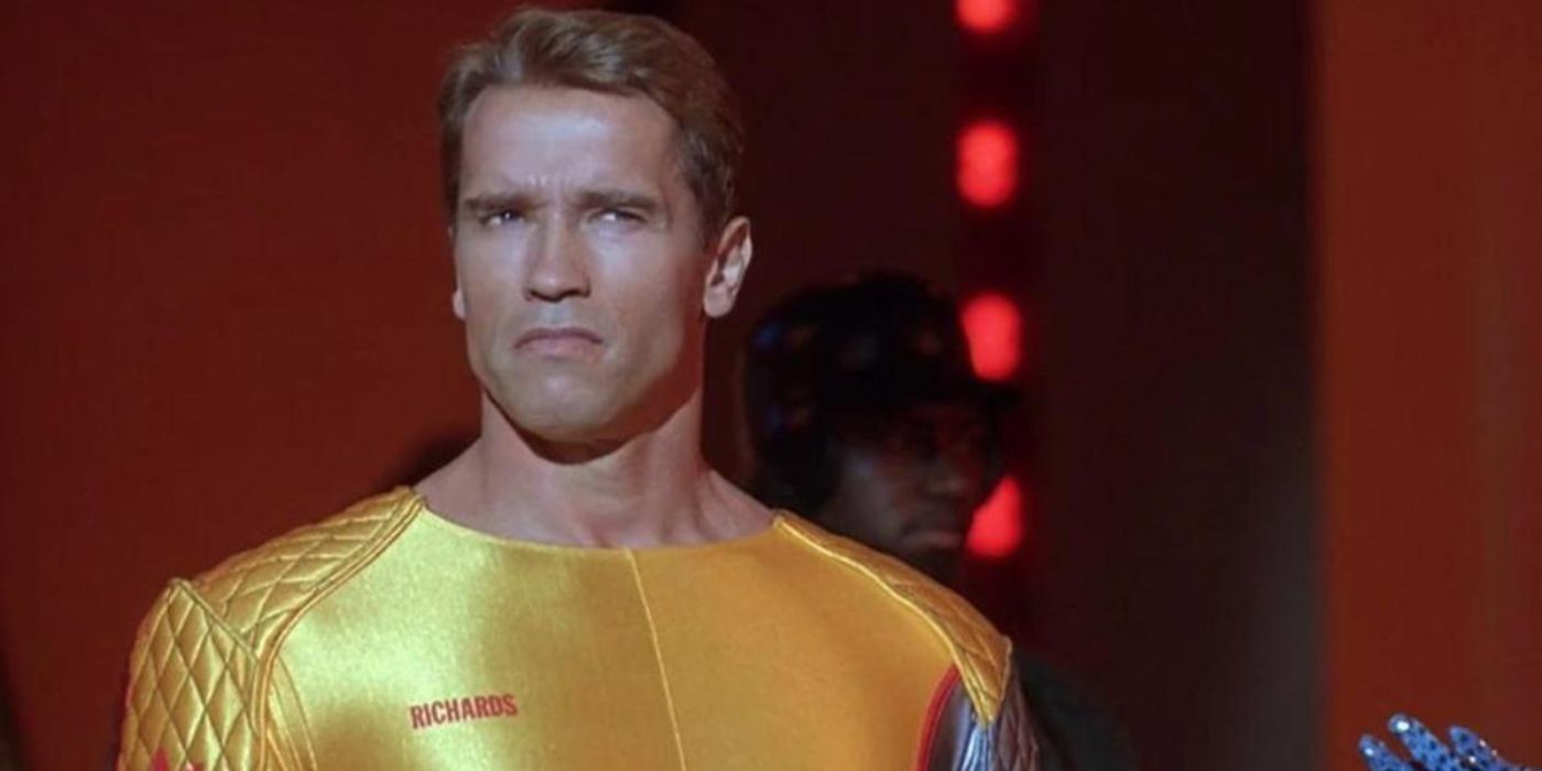 arnold schwarzenegger in a yellow jump suit ponders something off-screen