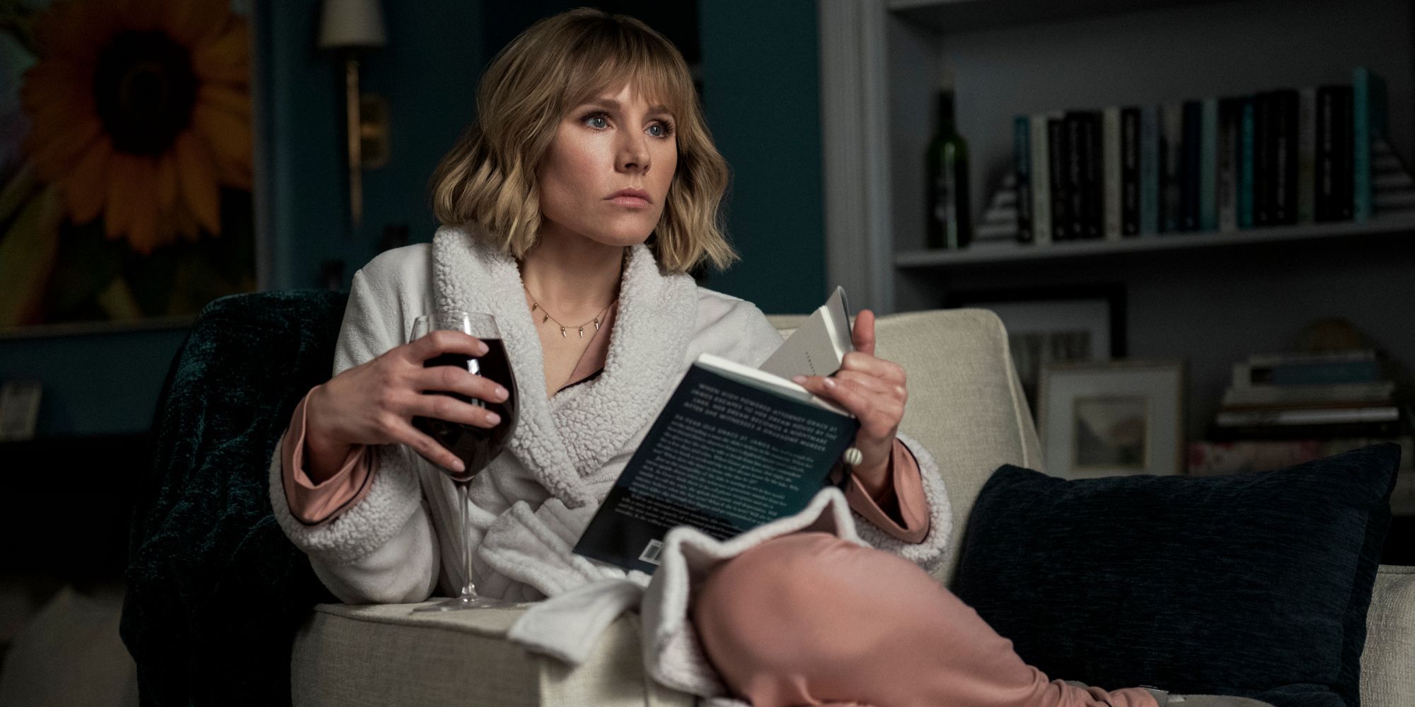 woman in the house kristen bell reading and drinking wine