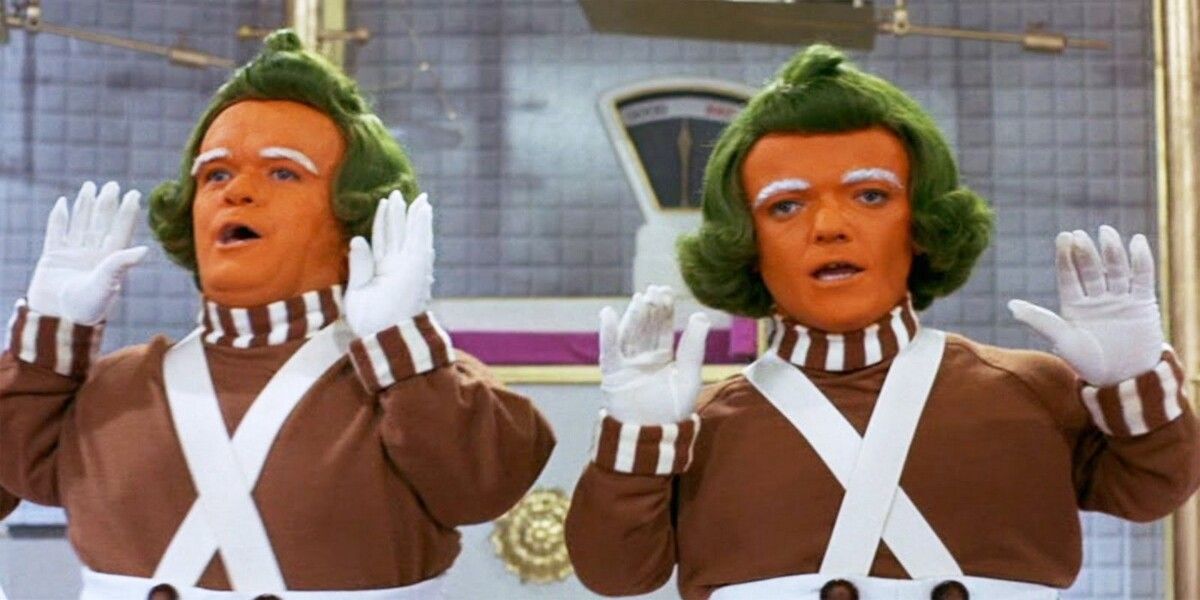 Oompa Loompas singing and holding up their hands in the 1971 film Willy Wonka and the Chocolate Factory