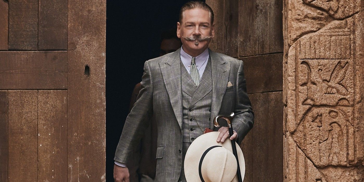 Hercule Poirot walking through a set of old wooden doors in Death on the Nile.