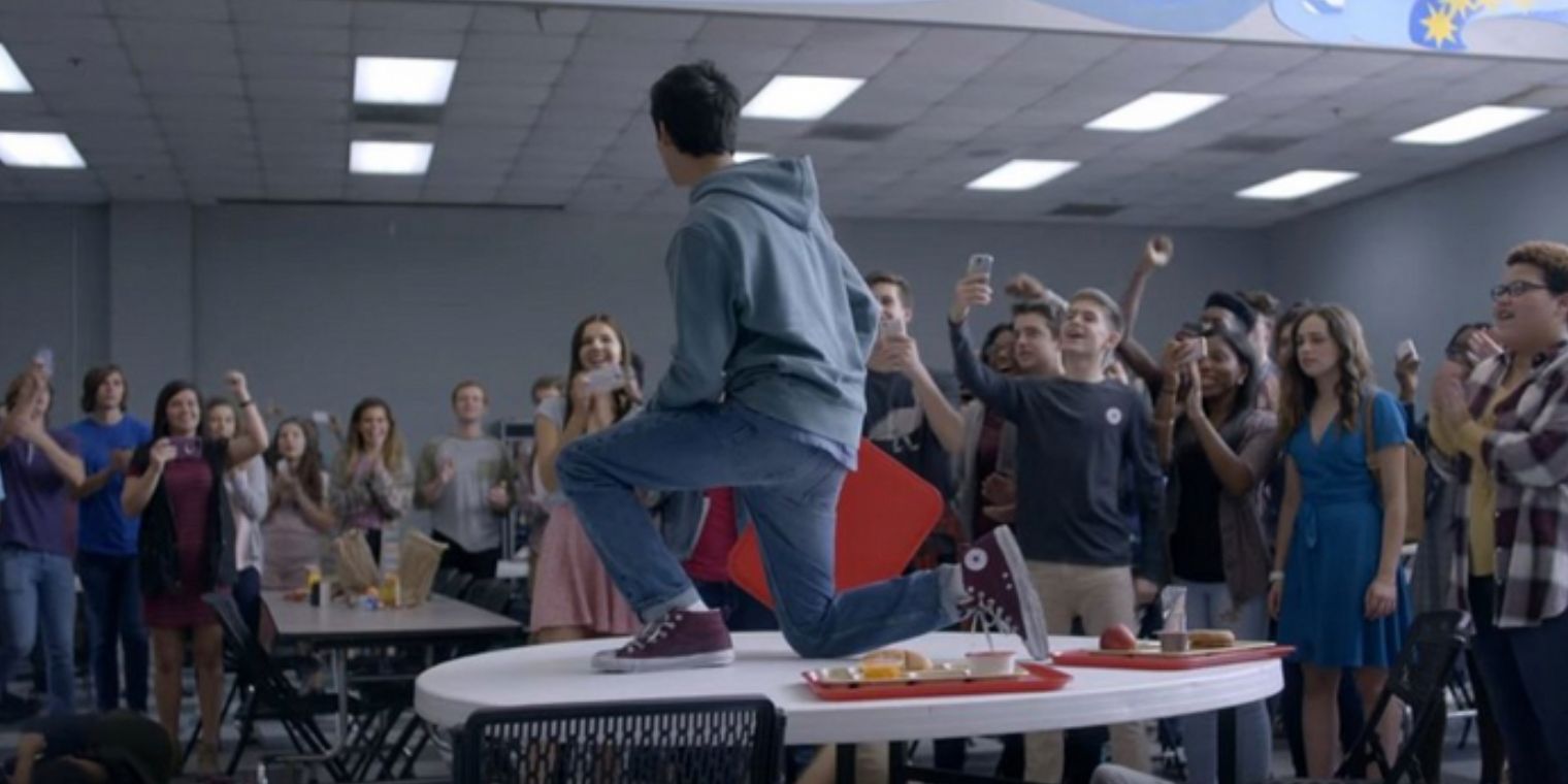Classmates take photos of Miguel on the cafeteria table after he fights his bullies in Cobra Kai