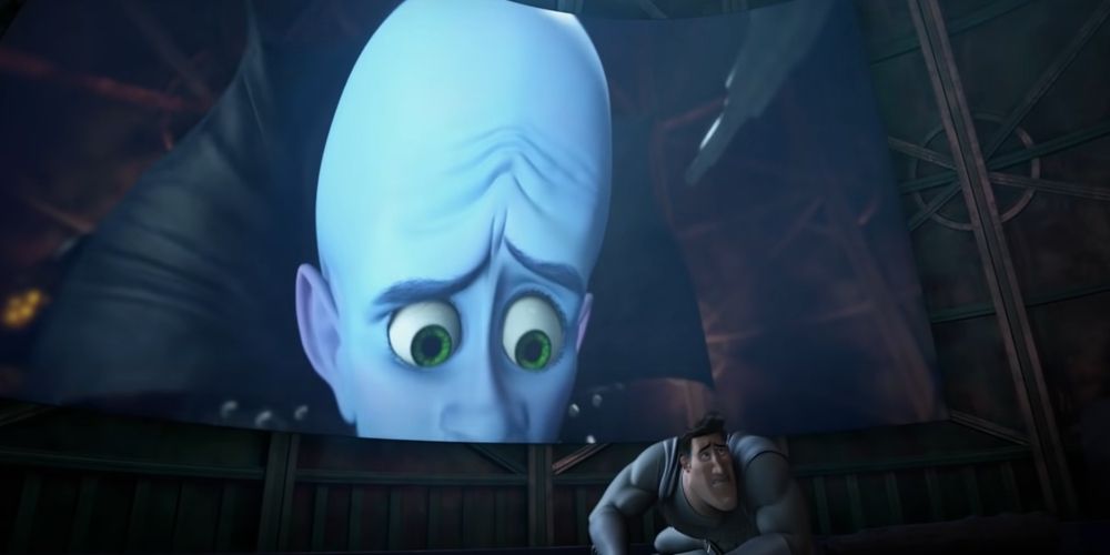 Metro Man cowers in a crouched position while Megamind watches with concern on a huge screen.