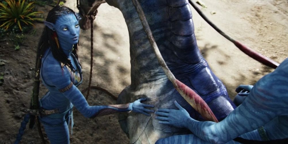 Neytiri helps Jake Sully mount an animal in Avatar movie