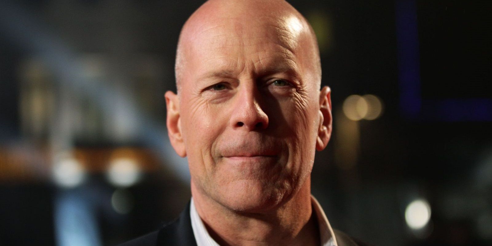 Bruce Willis smirks as he looks at the camera