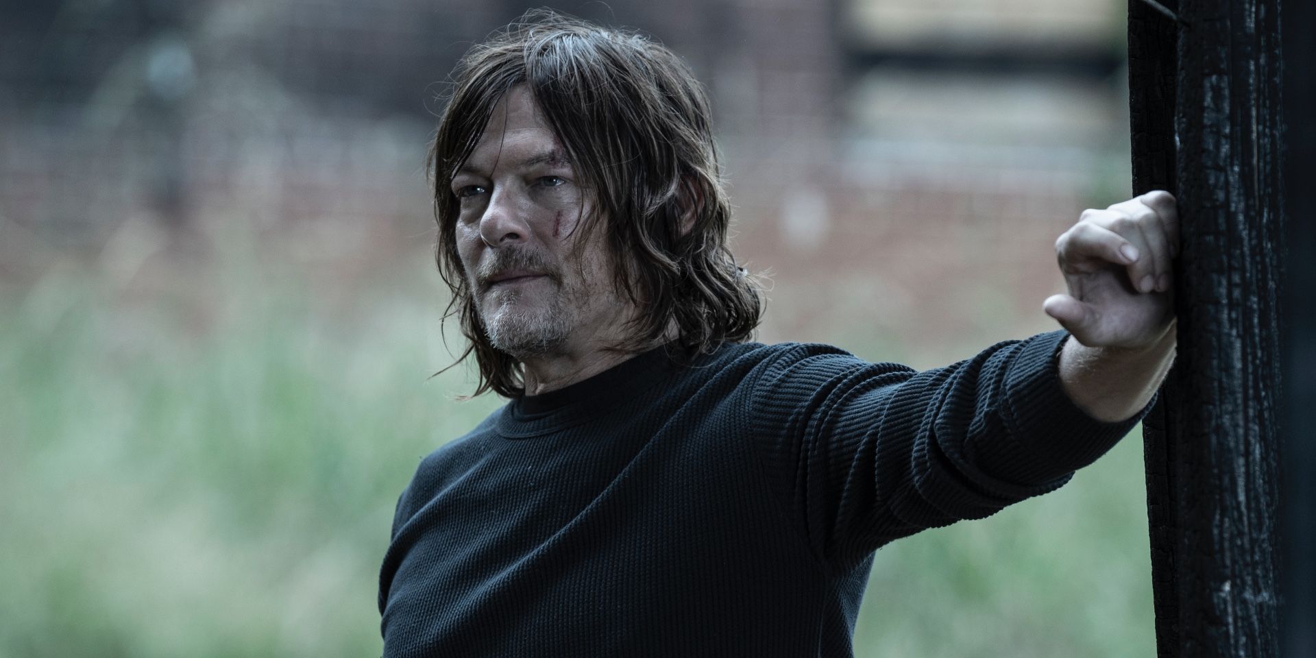 Daryl with long hair with his hand against a wall, somewhat smiling from The Walking Dead.