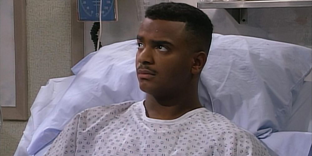 Carlton frowning while sitting in a hospital bed