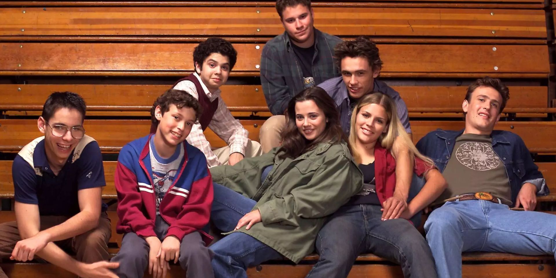 The teens from Freaks and Geeks sit on the gym bleachers.