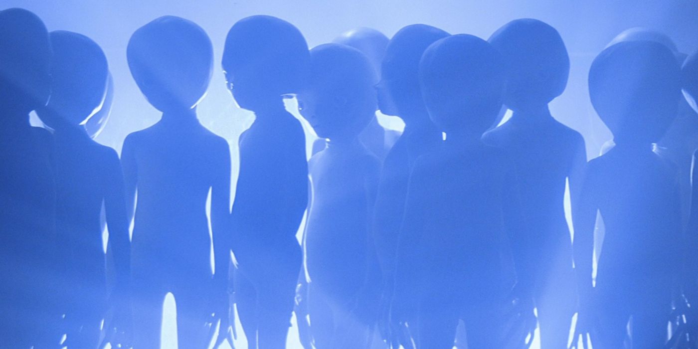 A blue tinted light showcases silhouettes of aliens from Close Encounters of the Third Kind.