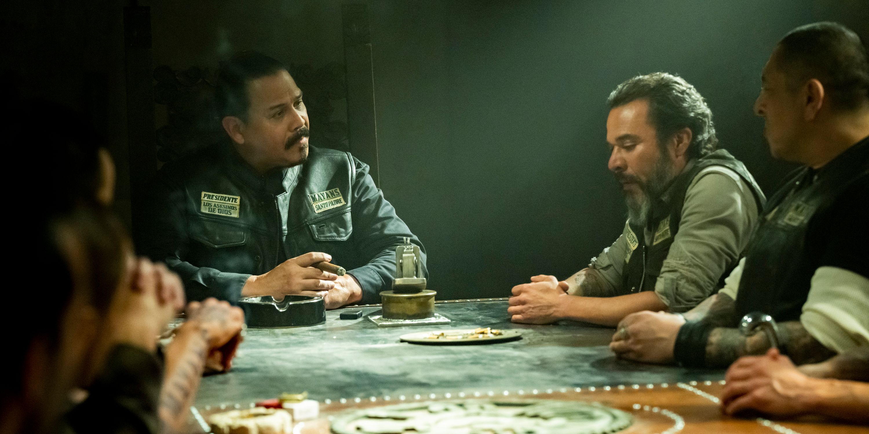 Several members of the Mayans M.C. club sitting around a table.