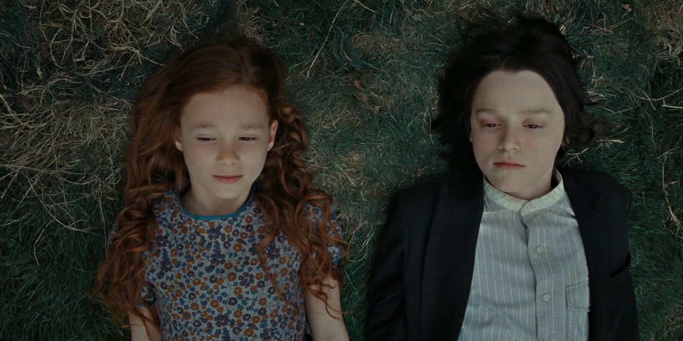 A young Lily Evans and Severus Snape lying side by side in the grass in Harry Potter 7