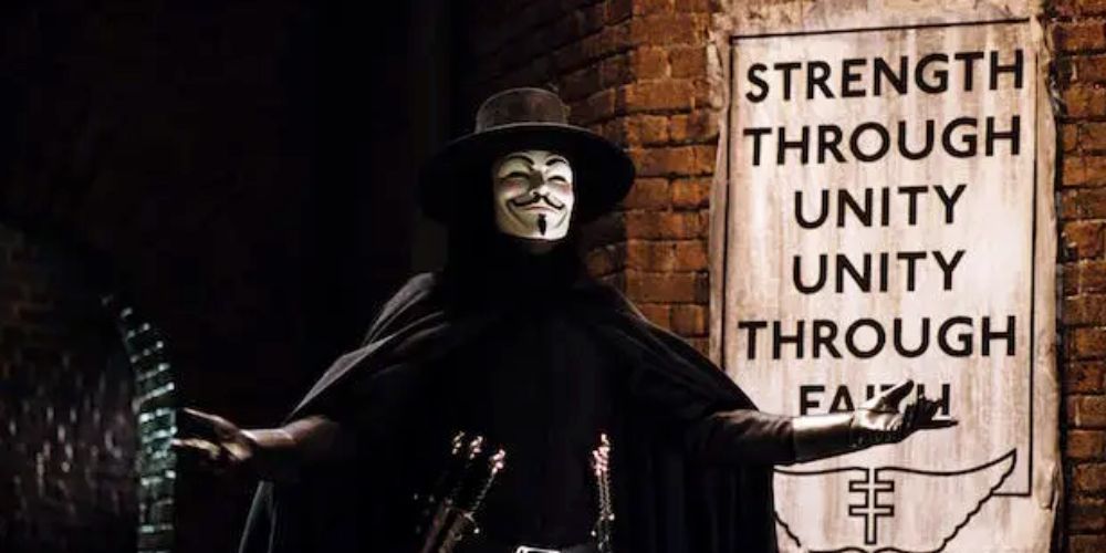 V from V For Vendetta standing in front of Strength Through Unity poster