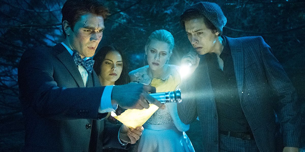 Archie, Betty, Jughead and Veronica using flashlights to look at a paper in the woods in Riverdale