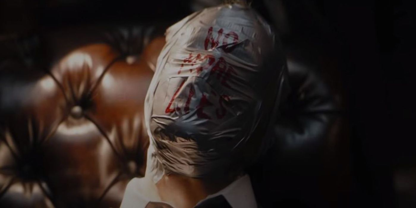 In a still from The Batman (2022), a dead body's face is wrapped in cling rap, with "NO MORE LIES" scrawled over the wrap in red letters.
