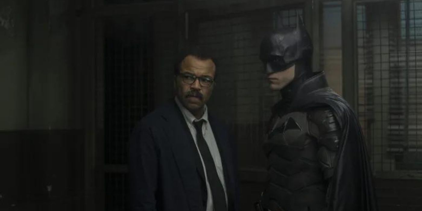 In a still from The Batman (2022), Batman and Commissioner Gordon watch something off-screen cautiously.