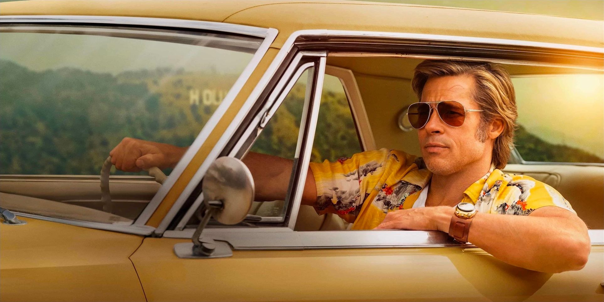 Bradd Pitt as Cliff Booth driving a yellow car in Once Upon a Time in Hollywood