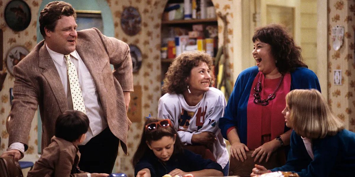 The Conner's family gathered around the table laughing in Roseanne