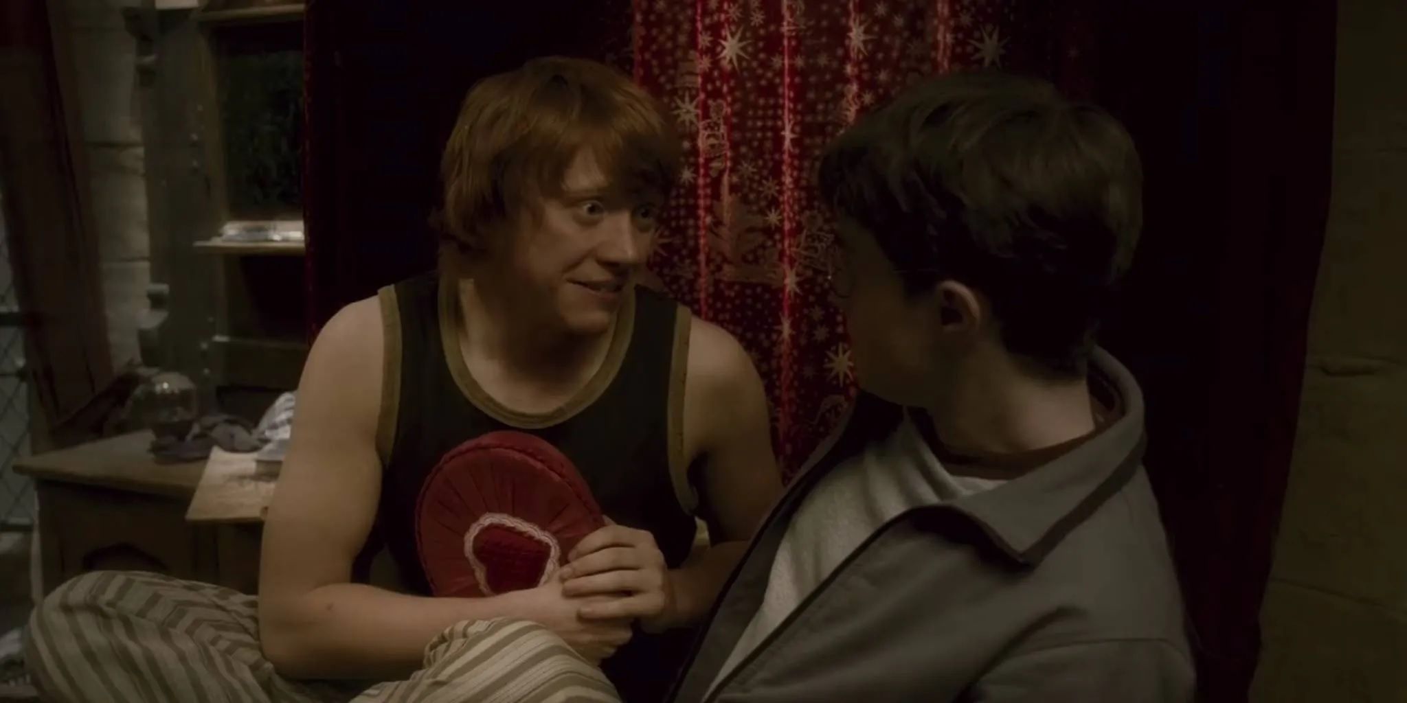 Ron Weasley under Love Potion influence smiling while holding chocolates