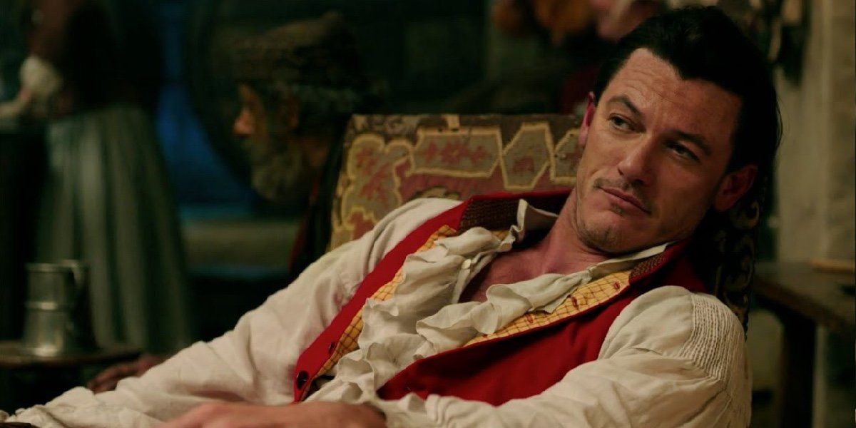 Gaston (Luke Evans) sitting in his chair being admired at the pub in 2017's Beauty and the Beast