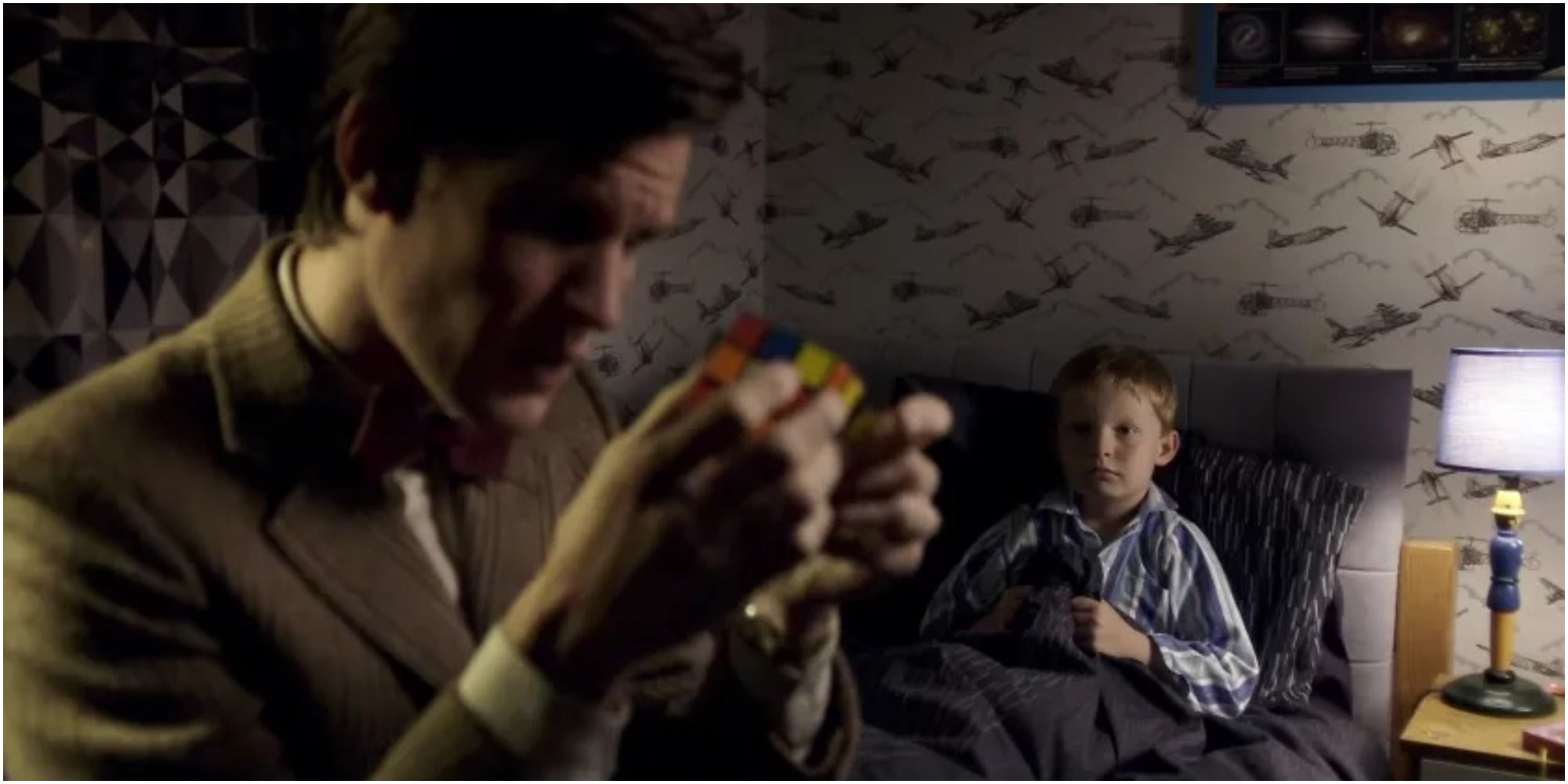 The Eleventh Doctor tries to help a scared child who is sitting in his bed in Doctor Who.