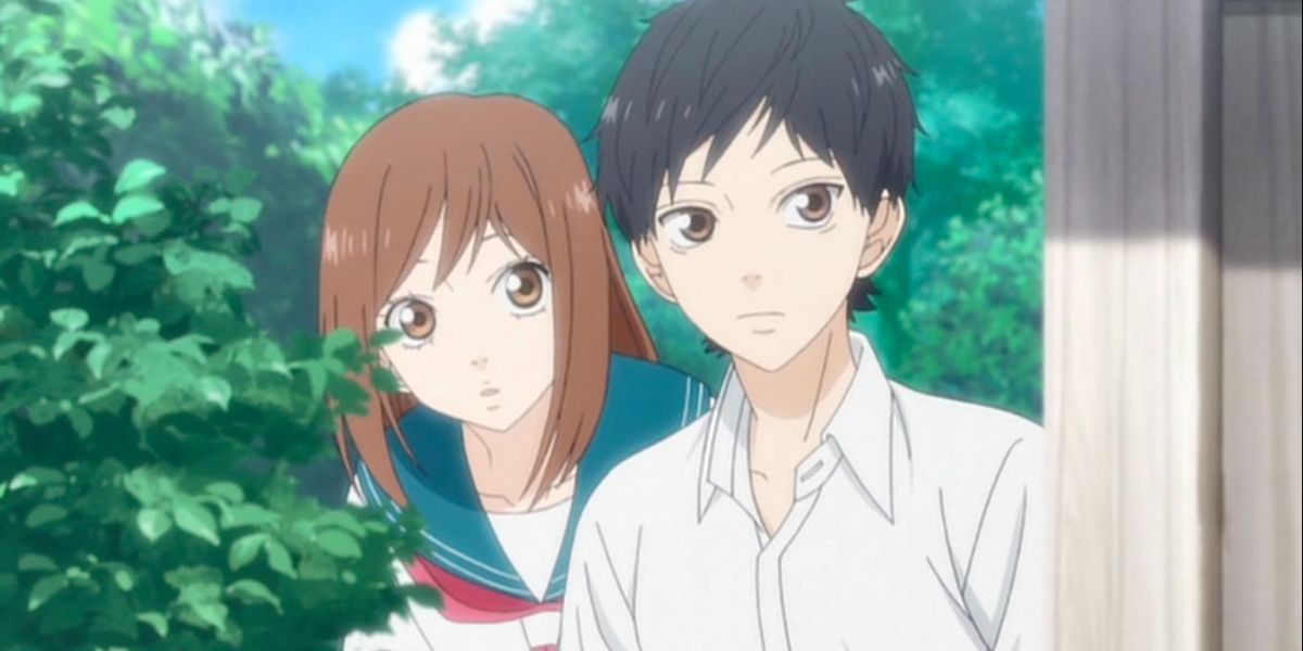 Image features a visual from Blue Spring Ride: (From left to right) Futaba Yoshioka (shoulder-length, brown hair and blue, white, and red school uniform) and Kou Mabuchi/Tanaka (short, black hair and white shirt) are hiding behind a building and a bush.